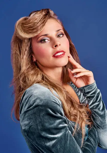 Cropped shot of a beautiful young woman styled in 80s clothing against a blue background