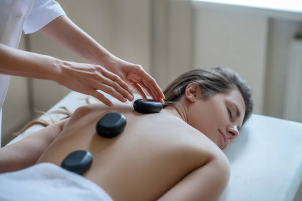 istock Massage therapist putting stones on a customers back 1270503277