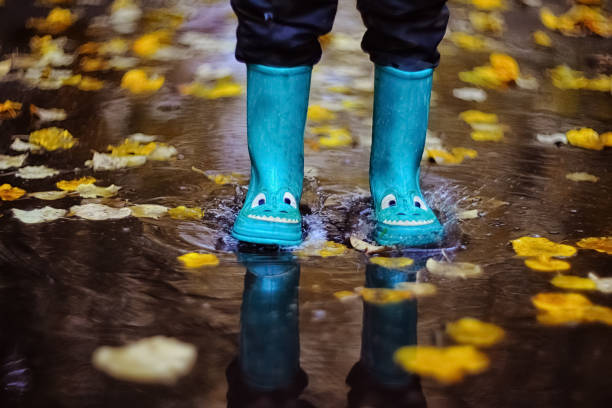 istock boy jumping in rubber boots through puddles in autumn 1270507884