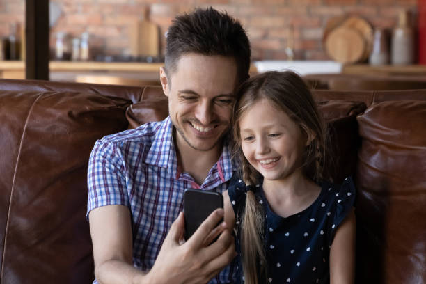istock Smiling father and little daughter using cellphone together 1270508837