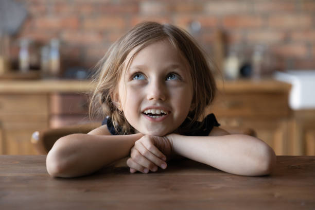 istock Cute little girl sit at table in kitchen singing 1270508875