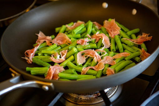 green beans with prosciutto being prepared in a skillet