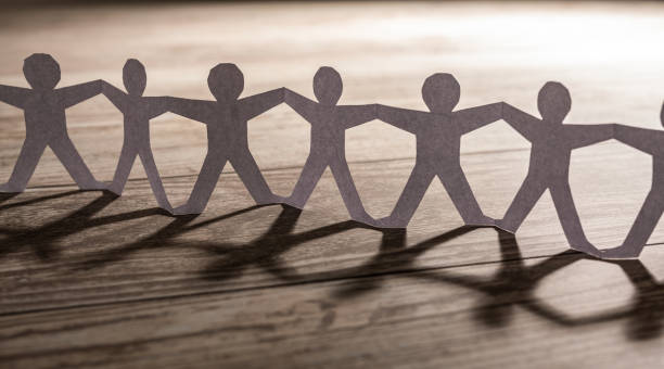 Human team of paper chain people. Team of paper chain people. Human chain with light and shadow. arm in arm stock pictures, royalty-free photos & images