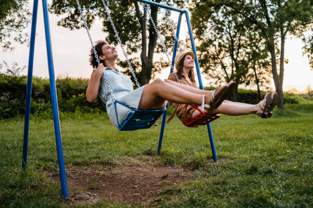 istock Two women riding swings in park 1270511097