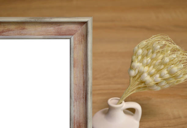 Closeup of part of mockup wooden frame with white clay vase with dry artificial plant on wooden background.