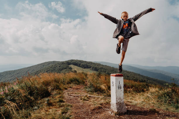 Boy jumping off a concrete post A boy taking a leap of faith. He is jumping off a state border post on top of a mountain range. leap of faith stock pictures, royalty-free photos & images