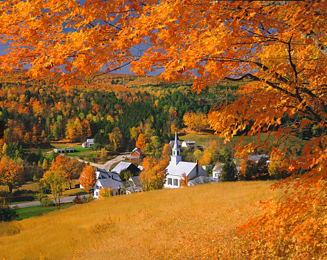 A Church and village sit in a valley surrounded by fall color filling the hillsides in Waits River in Topsham Township in Orange County of Vermont, USA.