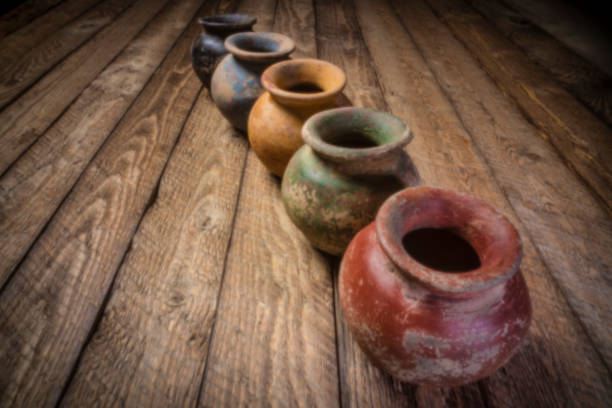 row os small grunge clay pots  with rough color finish on a weathered wood, soft focus image shot with lensless pinhole camera