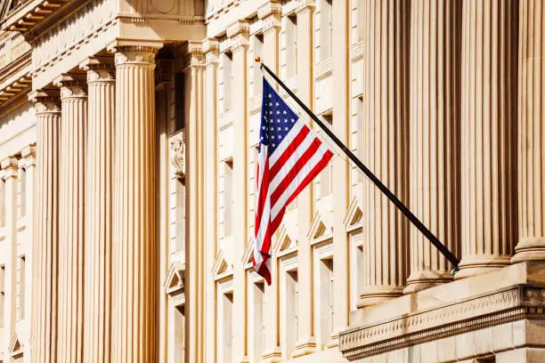 US flag over classical government building with columns in Washington, DC