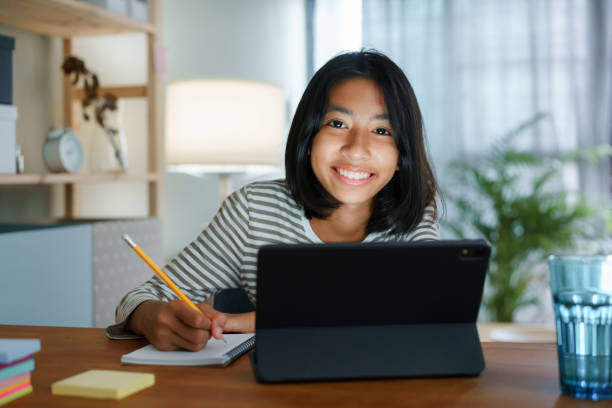 Homeschooling Asian girl doing homework And study online with tablet at the desk night. Portrait of Asia child happiness and smiling confidence looking to camera stock photo