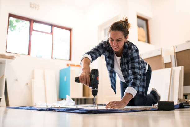 istock Concentrating kneeling woman drilling a screw in a kitchen cabinet 1270549404