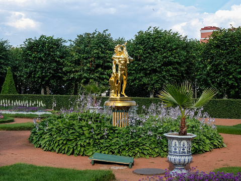 Gold statue surrounded by flowers in the Lower park of Peterhof, Russia
