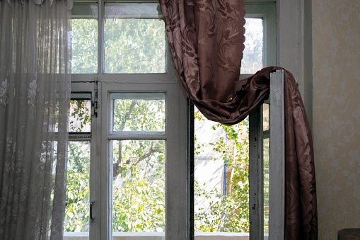 A dark curtain hanging on the open balcony door for better room airing