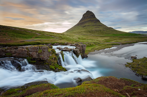 Amazing sunset the top of Kirkjufellsfoss waterfall with Kirkjufell mountain in the background on the north coast of Iceland's Snaefellsnes peninsula taken white a long shutter speed.