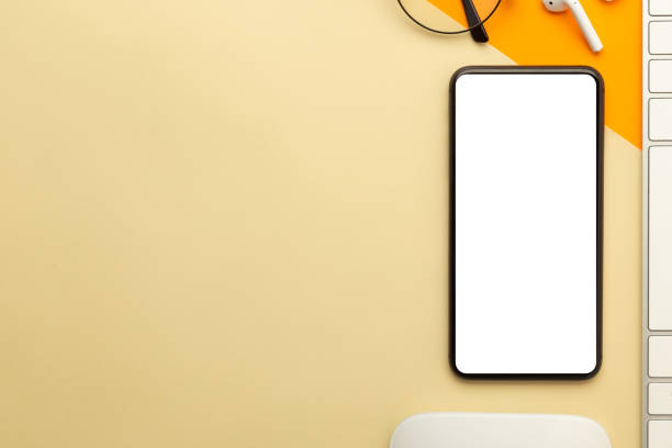 istock Flat lay, top view of orange office table desk with smartphone blank screen mockup with clipping path and wireless earphones, keyboard, mouse. Modern working space 1270561782