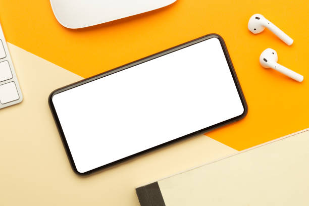 istock Flat lay, top view of orange office table desk with smartphone blank screen mockup with clipping path and wireless earphones, keyboard, mouse. Modern working space 1270561787