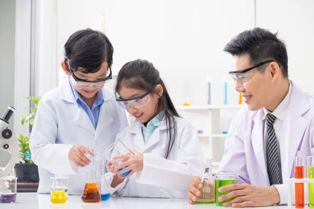 istock Young Asian boy and girl smile and having fun while learning science experiment in laboratory with teacher in classroom. Study with scientific equipment and tubes. Education concept. 1270562571