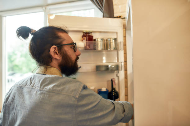 istock Young man, professional cook in apron taking ingredients out of the fridge while getting ready to prepare a meal, standing in the kitchen. Cooking at home concept 1270567745