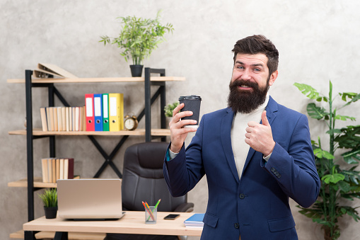 Must have stimulant for him. Man bearded manager businessman entrepreneur hold cup of coffee. Relaxed cheerful top manager drinking coffee. Boss enjoying energy drink. Worker start day with coffee.
