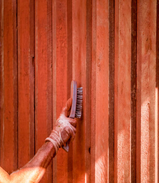 la main brosse la vieille couleur du mur de bois à prepair pour la nouvelle peinture de couleur rouge sur la maison à l’extérieur. - falun photos et images de collection