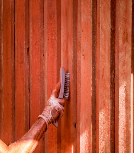 hand is brushing old color of wood wall to prepair for new painting of red color on house outside. - falun imagens e fotografias de stock