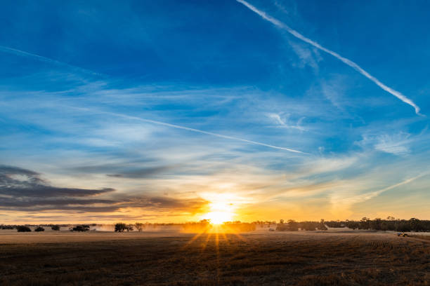 Sun sets over the open paddock land during harvesting season