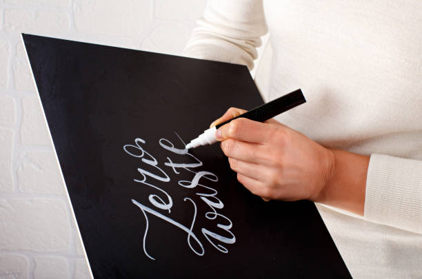 Woman writing on a small chalkboard zero waste lettering Woman writing on a small chalkboard zero waste lettering close up the human body writing black human hand stock pictures, royalty-free photos & images