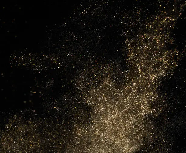 Photo of Gold glitter powder splash on black background