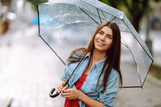 istock Cheerful woman under a transparent umbrella enjoying rainfall. 1270578690