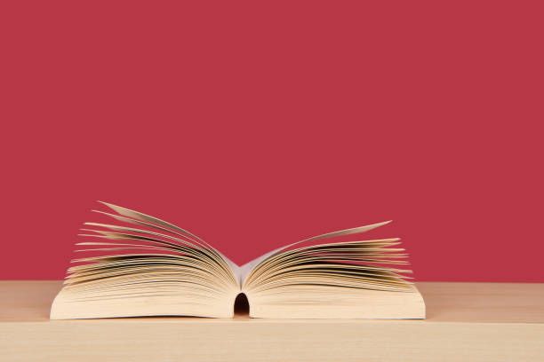 istock Open book with pages standing up lying on a bookplank on a red background 1270582908