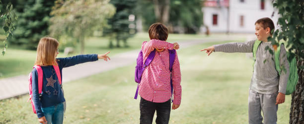 bambini con zaini in piedi nel parco vicino a scuola - bullying child teasing little boys foto e immagini stock