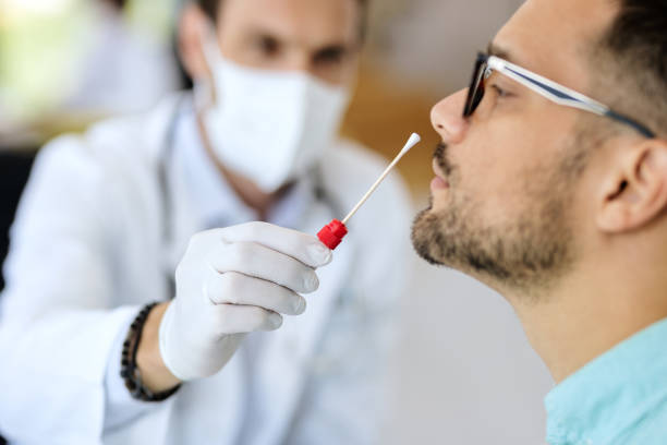 Close-up of a man having PCR test at medical clinic. Close-up of young man getting PCR test at doctor's office during coronavirus epidemic. epidemiology photos stock pictures, royalty-free photos & images