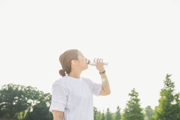 Attractive sporty woman drinking water from a bottle after jogging or running.