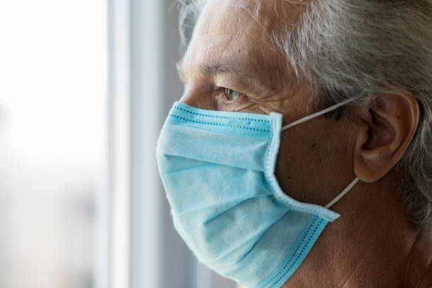 istock Old man with medical face mask looking through window 1270587917