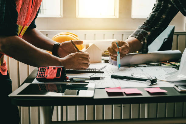 istock Engineer and contractor planning projects together at desk with blueprints. 1270588860