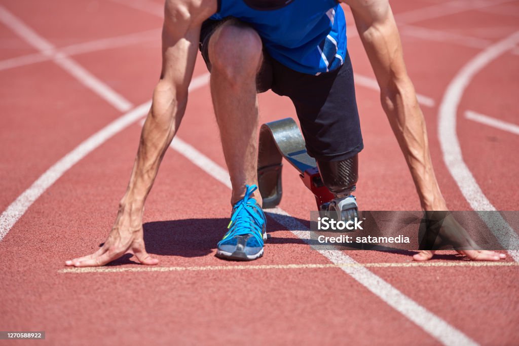 Adaptive sportsman starting point Close up of adaptive sportsman with prosthetic foot training on running track at the stadium on sunny summer day. Real bodies, diversity, recovery, adaptive sportsman training concept Athlete with Disabilities Stock Photo