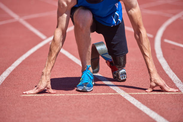 Adaptive sportsman starting point Close up of adaptive sportsman with prosthetic foot training on running track at the stadium on sunny summer day. Real bodies, diversity, recovery, adaptive sportsman training concept athlete with disabilities photos stock pictures, royalty-free photos & images