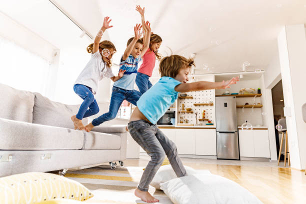 istock Playful kids having fun while jumping from sofa at home. 1270590227