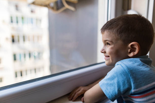 istock Profile view of happy boy looking through window. 1270590449