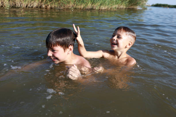 An older brother gently holds his baby sibling while swimming in the sea, sharing a joyful and heartwarming moment of family bonding and summer fun in the water. A perfect blend of love, care, and childhood adventure.