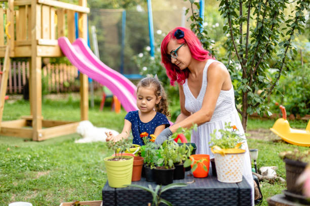 ハーブを植えるために彼女を助けながら、彼女の母親と素晴らしい時間を過ごしている楽しい小さな女の子 - oregano herb garden herb gardens ストックフォトと画像