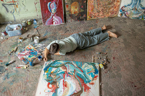 istock Boy lies on the floor and paints a canvas 1270592339