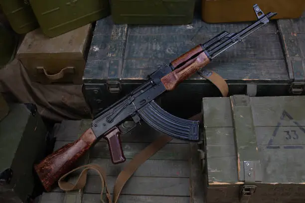 Kalashnikov AK 47 with ammunitions on army green box background. Text on ammunitions box in russian - cartridge type and caliber with lot number.