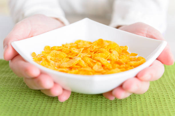 Female hands holding bowl with healthy breakfast made of cornflakes with milk