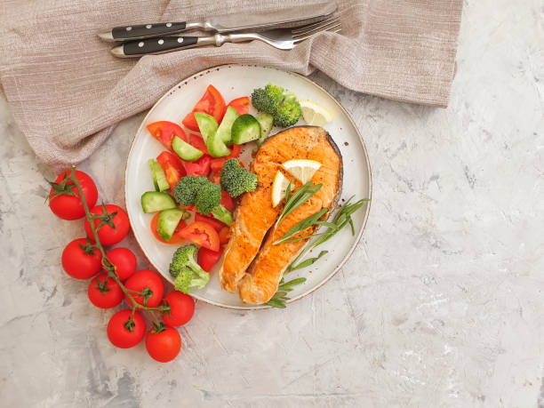 istock fried salmon piece on a plate, tomato on a concrete background 1270598619