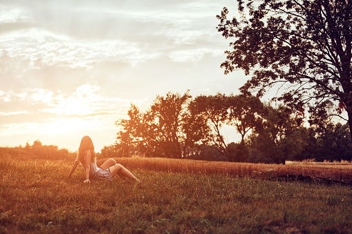 Silhouette of a woman sitting on a field.