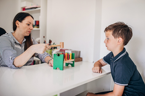 Close-up of a child building a toy tower out of wooden blocks, sitting in a living room at home