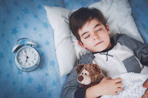 istock Six years old child sleeping in bed with alarm clock 1270614700