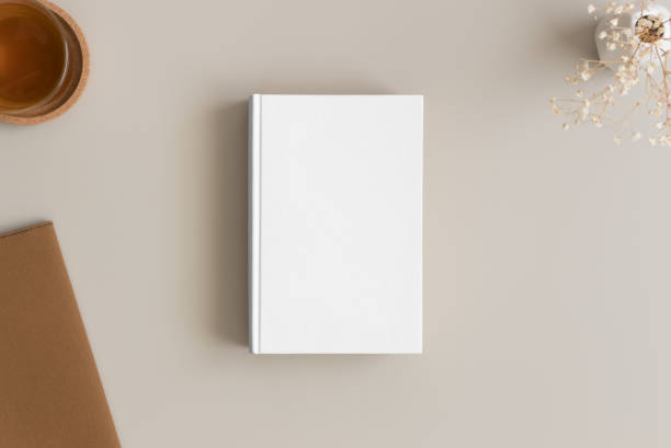 istock White book mockup with a cup of tea and workspace accessories on a beige table. 1270614828