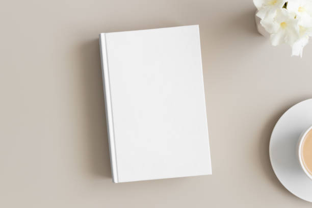 istock White book mockup with a cup of coffee and oleander on a beige table. 1270615413